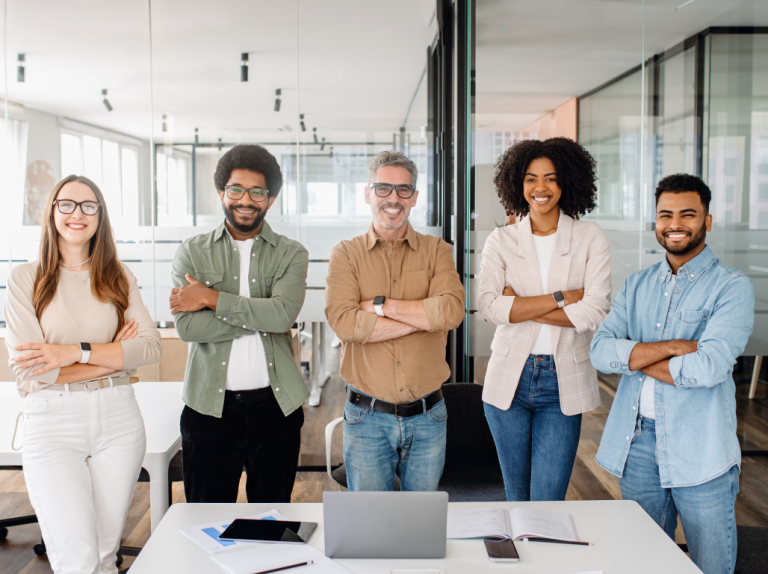 A diverse group of colleagues stands confidently, showcasing their readiness for business challenges after cross-cultural training.