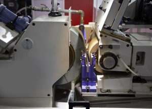 A photo depicting the wheels in centerless grinding in operation within a high precision industrial CNC centerless grinding machine.