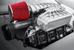 A supercharger shown connected to the engine of a vehicle.