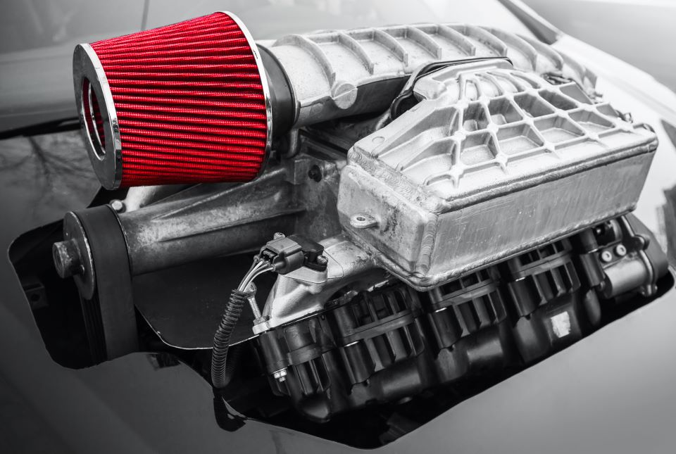 A supercharger shown connected to the engine of a vehicle.