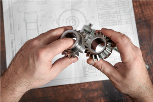 An engineer examining bevel gears over engineering drawings before bevel gear testing.