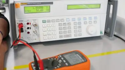 Calibration setup with a digital multimeter connected to a calibrator to reduce electrical measurement errors.